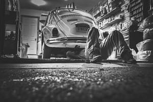 Man fixing under a VW beetle